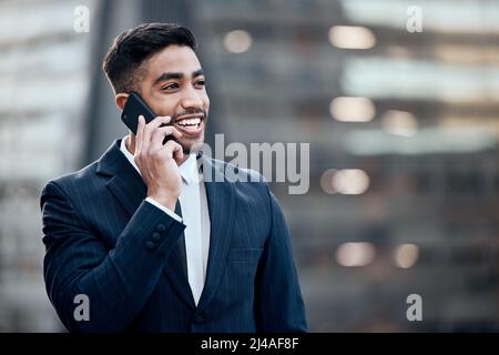Ill be there shortly. Shot of a handsome young businessman standing alone outside and using his cellphone. Stock Photo