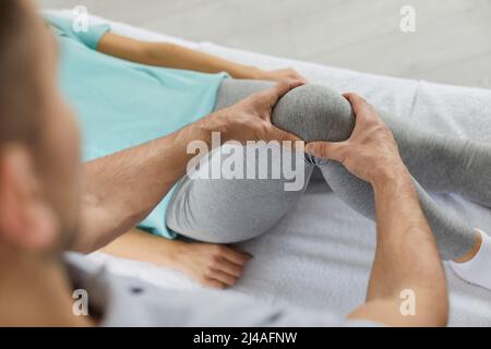 Physiotherapist or chiropractor at physiotherapy clinic helping patient with knee pain Stock Photo