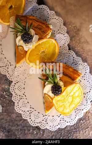 top view of two slices of tiramisu dessert with berries and an orange slice. Stock Photo