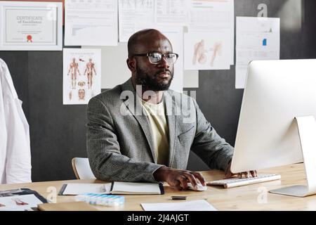 Serious African businessman working on computer at his workplace at office Stock Photo