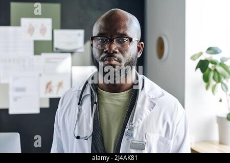 Portrait of African male doctor in eyeglasses and white coat looking at camera with serious expression Stock Photo