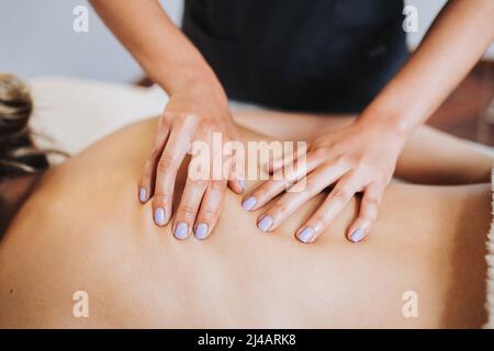 Unrecognizable therapist making back and spine massage to a female patient. Relaxing and de-stress Stock Photo