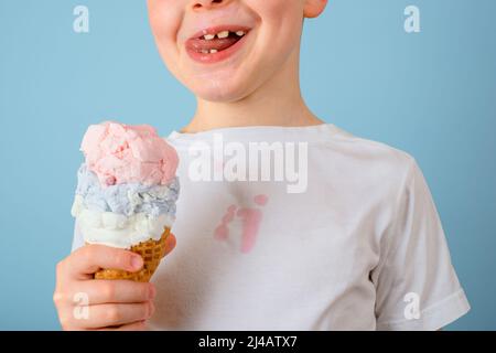 The boy licking ice cream closed his eyes. dirty stain of ice cream on white clothes. daily life stain and cleaning concept. High quality photo Stock Photo