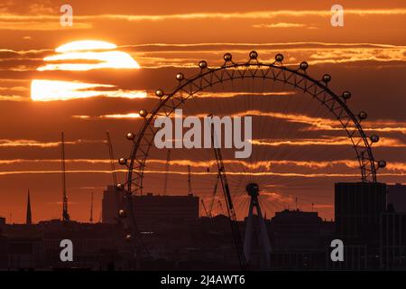 London, UK. 13th April, 2022. UK Weather: Dramatic sunset behind London Eye ferris wheel starting the Easter weekend heatwave. Credit: Guy Corbishley/Alamy Live News Stock Photo