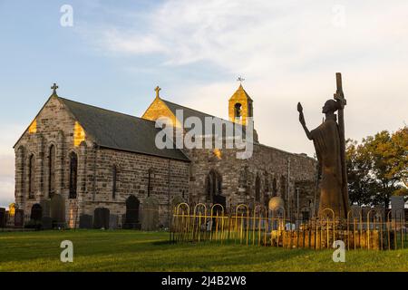 Parish Church of St Mary the Virgin on Holy Island with the statue of St Aidan in foreground Stock Photo