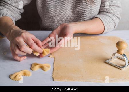 Fresh pasta dough rolled out with hands in shot making farfalle shapes. Stock Photo