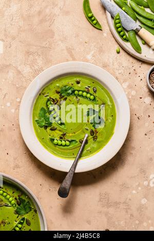 Green pea soup in a bowl, with sugarsnap peas and seasoning. Stock Photo