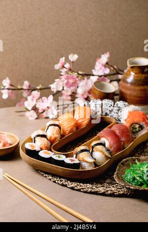 Sushi rolls set. Traditional japanese dish sushi rolls with fresh salmon, tuna, eel, prawns on rice. Serving on wooden plate with soy sauce, wakame sa Stock Photo