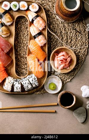 Sushi rolls set. Traditional japanese dish sushi and rolls with fresh salmon, tuna, eel and prawns on rice. Serving on wooden plate with soy sauce, sa Stock Photo