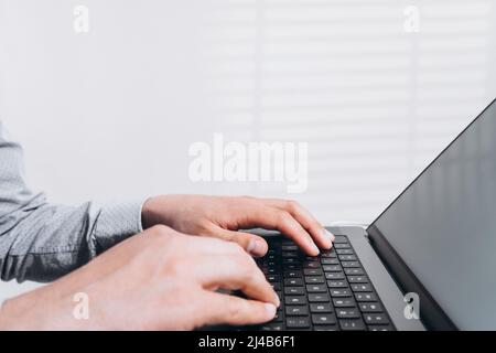 Programmer man hands typing on laptop computer keyboard and surfing the internet on office table. Distance learning, working from home, business and Stock Photo