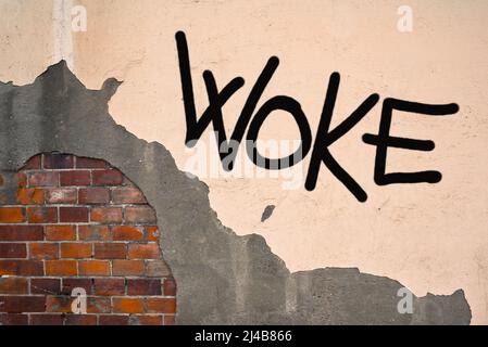 Handwritten graffiti Woke sprayed on the wall, anarchist aesthetics. Text of progressive activism. Stock Photo