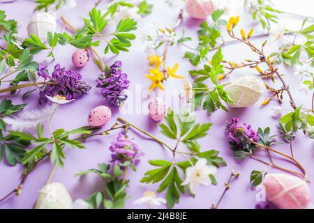 Easter floral background. Eggs with spring blossoming white yellow flowers on purple background. Symbolic holiday texture. Top view Stock Photo