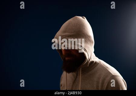 man with hood on a dark background depression or hacker Stock Photo