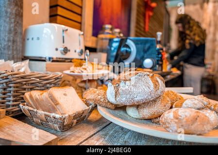 Assorted fresh breads in plate and basket on wooden table in hotel Stock Photo