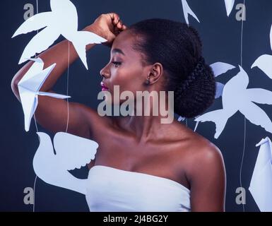 Soar with the energy of your own unique spirit. Studio shot of a beautiful young woman posing with paper birds against a black background. Stock Photo