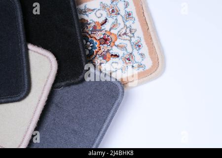 Carpet. Floor covering samples. Multi-colored rug with stitched edges. Close-up on a white background. Stock Photo