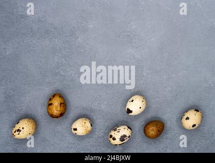 Quails Eggs in a raw on the gray stone background. Place for the text. Easter composition.Flat lay, top view. High quality photo Stock Photo