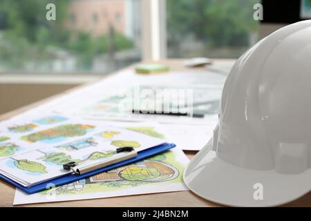 Landscape designer's projects with hardhat on table in office Stock Photo