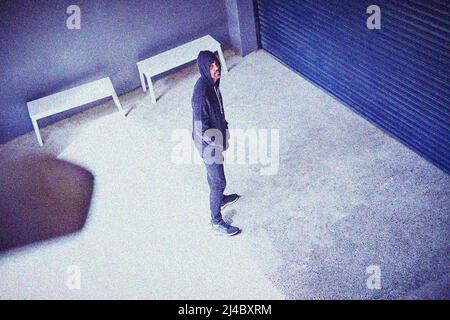 Hes got crime on his mind. High angle shot of a sketchy-looking man standing outside a building. Stock Photo