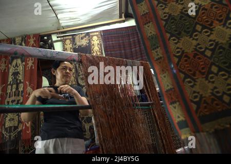 Weaving artists Ni Wayan Sudiati preparing yarns for traditional weaving in the traditional village of Tenganan Pegringsingan in Karangasem, Bali, Indonesia. Stock Photo