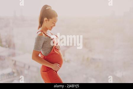 Asian pregnant woman happy touching her pregnancy bump for prenatal photoshoot wearing maternity clothes overalls. Beautiful young multiracial girl Stock Photo