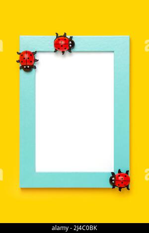 Blue frame with white card and ladybugs on yellow background. Mockup, Top view, Flat lay. Layout, template for your design. Stock Photo