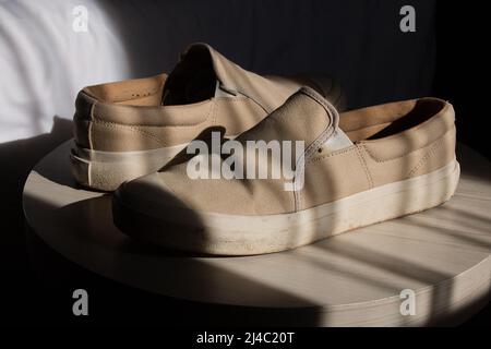 a pair of cream-colored shoes, kept on a round table Stock Photo