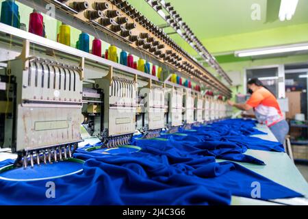 A worker working with sewing machine, Embroidery area in textile factory in industrial zone with modern machinery and technology systems. select focus Stock Photo