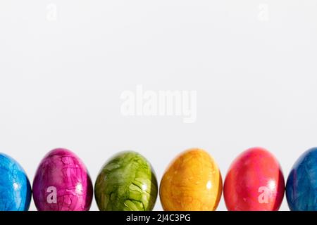 Many Easter eggs arranged in one row on a white background. Easter. Stock Photo