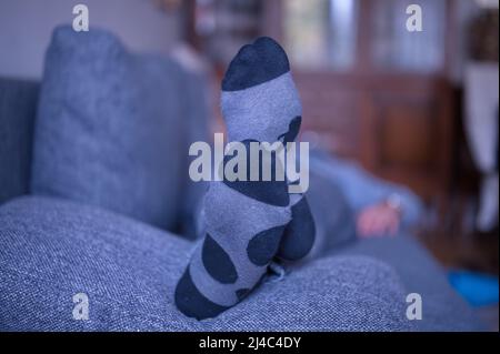Man lying on a couch in the living room with warm socks Stock Photo