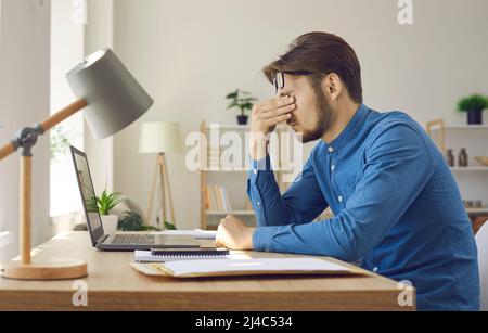 Man sitting at working desk tired of paperwork and feeling eye strain from laptop Stock Photo