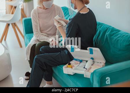 Nurse checking health of senior woman in living room Stock Photo