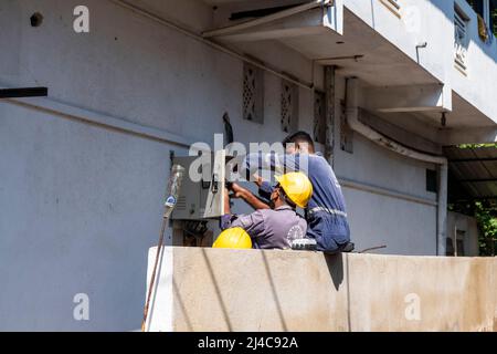 three man fixing electricity box. Stock Photo