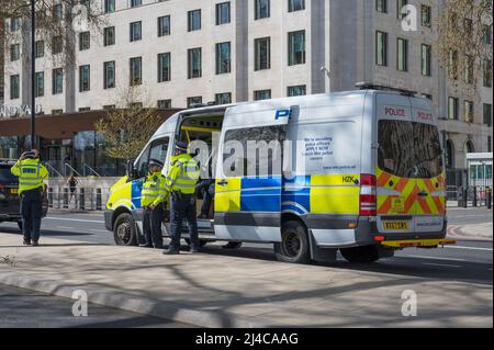 London Metropolitan police officers stand alongside a police support unit van parked on Victoria Embankment opposite New Scotland Yard. London, UK. Stock Photo