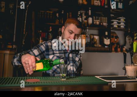 Bartender pouring green banana liqueur into shot glass while preparing cocktail Green Mexican Stock Photo