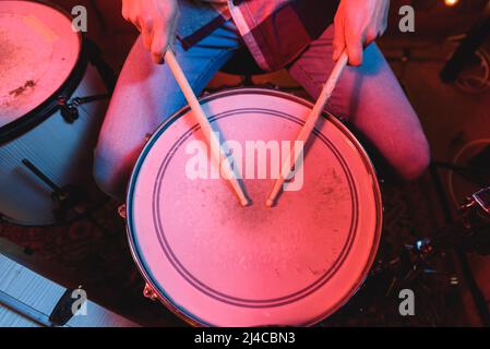 From above of talented crop anonymous male musician playing drums with drumsticks while performing song on stage during live concert Stock Photo