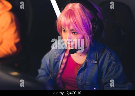 professional girl gamer with headphones playing and streaming online game medium closeup indoors cyber sport concept. High quality photo Stock Photo