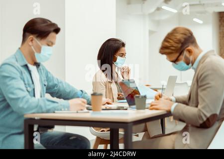 Two men and woman sitting at the table in the office Stock Photo