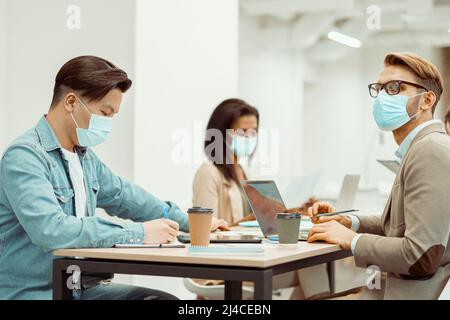 Two men and woman working at the table in the office Stock Photo
