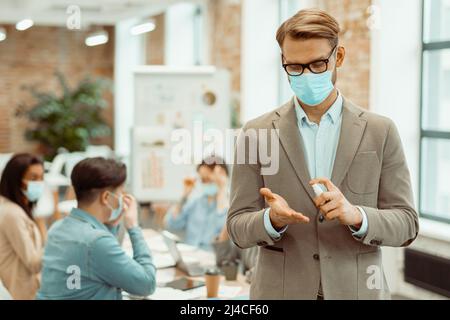 Male employee sanitizing hands in the office Stock Photo