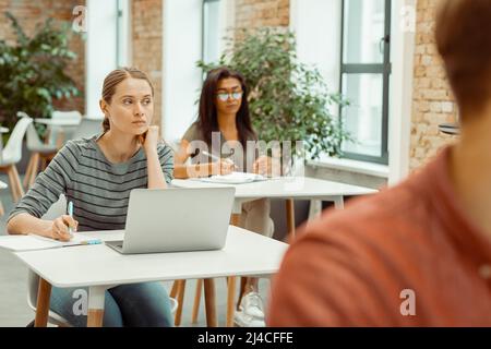 Female student sitting at table and using laptop Stock Photo