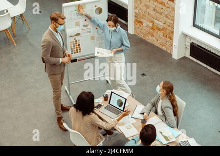 Two colleagues standing near flipchart in the office Stock Photo