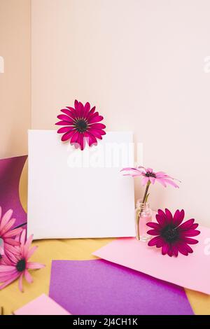Mockup image with a white canvas surrounded by color papers and flowers Stock Photo