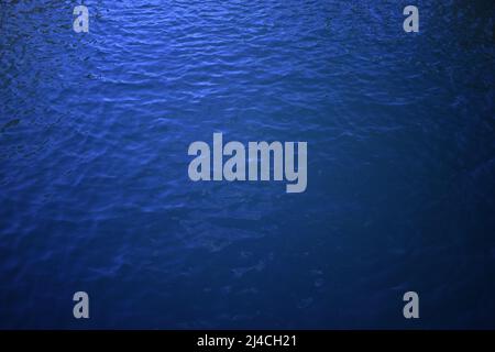 Dark blue wavy water surface. Swimming pool water texture. Blue liquid reflections. Still rippled water of seashore. Swimming pool surface texture. Na Stock Photo