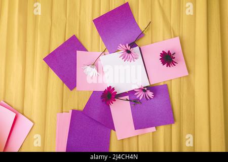 Mockup image with a white canvas surrounded by color papers and flowers Stock Photo