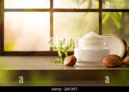 Detail of moisturizing cream with almond extract on wooden tableand window background. Front view. Horizontal composition. Stock Photo
