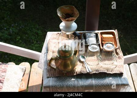 Coffee drip pot glass jar, Brass kettle jar, sugar sachet and biscuits Stock Photo