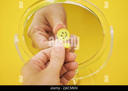 Conceptual image of happiness and wellness of a smiley face reflected in a mirror in yellow color Stock Photo
