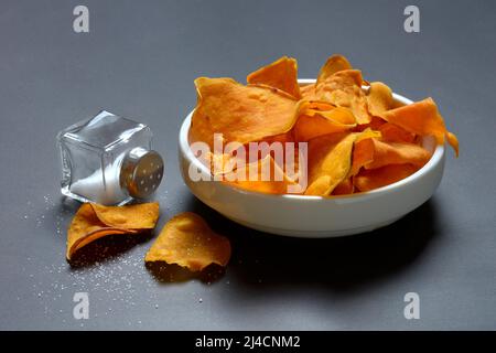 Sweet crisps in skin and salt container, sweet potato (Ipomoea batatas) Stock Photo