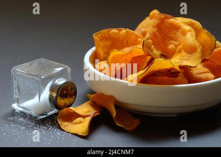 Sweet crisps in skin and salt container, sweet potato (Ipomoea batatas) Stock Photo